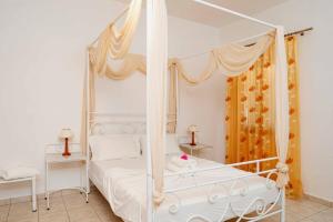 a white bedroom with a four poster bed at Apolafsis Studios in Patmos