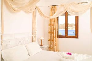 a bedroom with a white bed and a window at Apolafsis Studios in Patmos