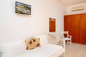 a living room with a white couch and a tv on the wall at Apolafsis Studios in Patmos