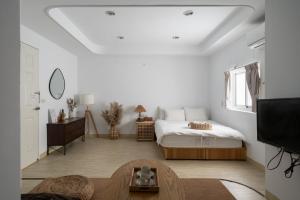 een witte slaapkamer met een bed en een televisie bij MH Alley in Tainan