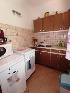 a kitchen with a white stove and a sink at Zöld Liget Vendégház in Balatonfenyves