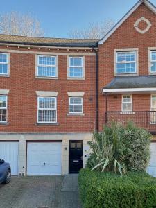 a brick house with two garage doors and a car at Curb Properties - Gorgeous 3 Bedroom House Close To Town Centre in Cheltenham