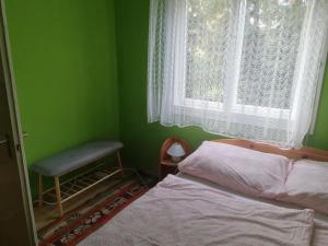 a green bedroom with a bed and a window at Zöld Liget Vendégház in Balatonfenyves