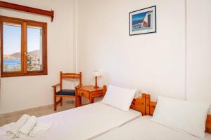 a bedroom with two beds and a chair and a window at Apolafsis Studios in Patmos