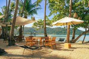 - une table, des chaises et un parasol sur la plage dans l'établissement Solario Beachfront Villa - Koh Chang, à Ko Chang