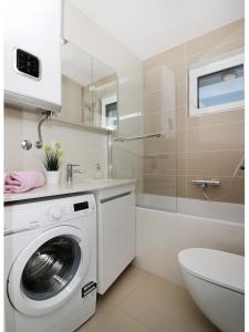 ein Badezimmer mit einer Waschmaschine und einem Waschbecken in der Unterkunft Royal Primošten in Primošten