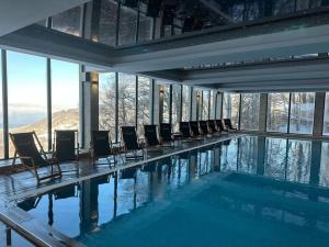 a swimming pool with chairs in a building at Kopaonik Milmari Spa and Wellness Wooden Horn S21 in Kopaonik