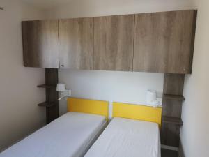 Habitación pequeña con 2 camas y armario en Ô Doubs Chalets, en Mouthe