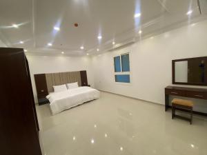 a white bedroom with a bed and a television at شقق فلورنيسا الفندقيه in Taif
