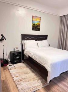 a bedroom with a large white bed and a lamp at Lovely 3 bedroom with a view of the park in Machakos