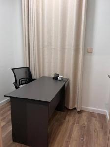 Un escritorio negro en una habitación con una cortina. en Lovely 3 bedroom with a view of the park, en Machakos 2 fotos más