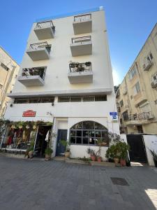 a white building with balconies on a street at Adorable 2 bedrooms apt w Bomb Shelter next to the beach in Tel Aviv