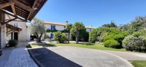 podjazd prowadzący do domu z drzewami i krzakami w obiekcie "LA ROCHELLE LODGE" Chambres d'Hôtes w mieście Sainte-Soulle