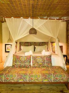 a bedroom with a large bed with a canopy at Vila Botanika Caraíva in Caraíva