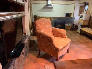 an orange chair in a living room with a fireplace at El Corral de Baxo in Felechosa