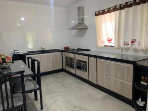 a kitchen with wooden cabinets and a table and a window at Casa com piscina aquecida e mesa de sinuca in Araquari