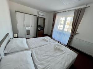 um quarto com 2 camas brancas e uma janela em BASELINE športový areál & penzión em Banská Bystrica