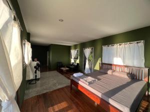 - une chambre avec un grand lit aux murs verts dans l'établissement Char Bungalows, à Koh Tao