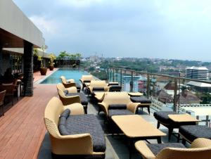 a balcony with tables and chairs and a swimming pool at Louis Kienne Simpang Lima in Semarang
