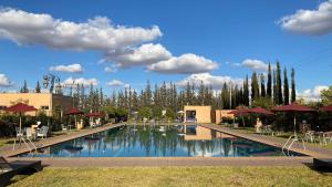 a swimming pool with tables and umbrellas in a resort at Palais Benfatah in Marrakesh