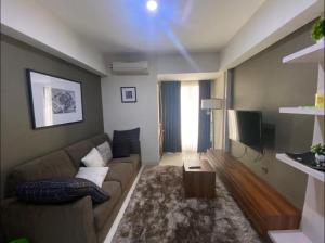 a living room with a couch and a television at Louis Kienne Simpang Lima in Semarang