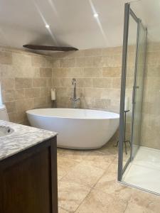 a large white tub in a bathroom with a shower at Arms Cottage in Bridge