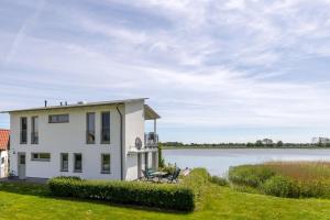 een wit huis met uitzicht op een meer bij Ferienwohnung Boddenblick in Puddemin