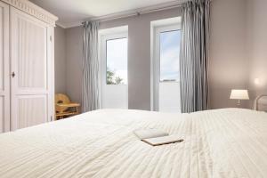 a bedroom with a white bed with a book on it at Ferienwohnung Seeblick in Puddemin