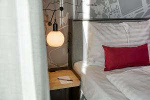a bedroom with a bed with a red pillow and a table at IntercityHotel Berlin Airport BER in Schönefeld