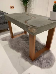 a concrete table with a furry rug under it at Lavish The Marble Apartment in Bury Saint Edmunds