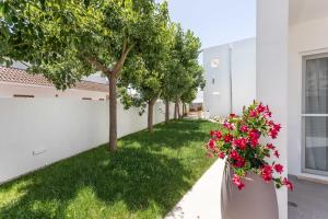 een tuin met rode bloemen in een vaas naast een gebouw bij Blu Marine Residence in Porto Cesareo