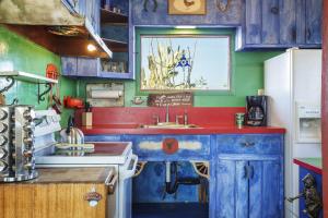 a kitchen with blue cabinets and a white refrigerator at The Cabin Under the Stars - Hot Tub, BBQ and a Firepit cabin in Joshua Tree
