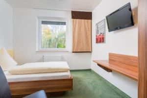 a small room with a bed and a tv at Hotel zur Post in Hemmingen
