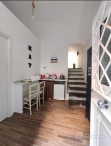 a room with a staircase and a kitchen with white walls at Al Vicolo di Ercolano in Ercolano