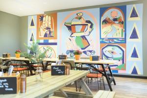 波茨坦的住宿－the niu Amity，一间设有桌子和壁画的用餐室