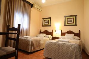 a hotel room with two beds and a table at Hostal Rocio in Sanlúcar la Mayor