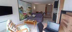 een woonkamer met een bank en een tafel met een laptop bij Superbe appartement avec piscine chauffée et parking privé - La Clé Chaumoise in La Rudelière