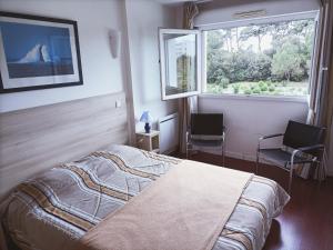 una camera con un letto e una finestra con due sedie di Superbe appartement avec piscine chauffée et parking privé - La Clé Chaumoise a La Rudelière