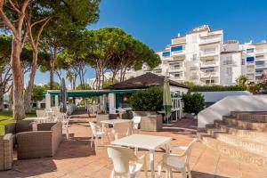 a patio with tables and chairs and a building at Beachside Luxury Apartment in Puerto Banus - Club Playas del Duque in Marbella