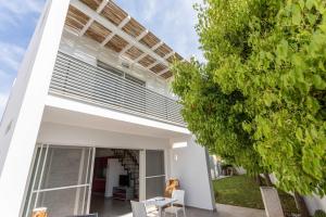 une maison blanche avec un arbre devant dans l'établissement Blu Marine Residence, à Porto Cesareo
