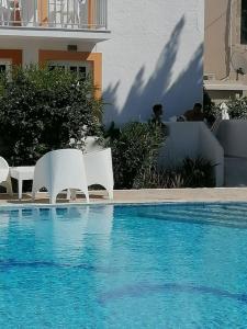 two white chairs sitting next to a swimming pool at Katerina Apartments in Kalymnos