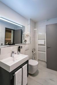 a bathroom with a sink and a toilet and a mirror at Hotel Kreis Residenz München in Munich