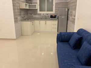 sala de estar con sofá azul y cocina en شقق فلورنيسا الفندقيه, en Taif