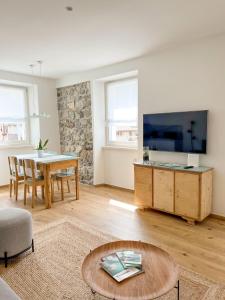 sala de estar con mesa y TV de pantalla grande en Sant'Antòni Apartments, en Tenno