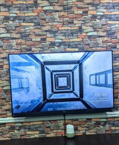 ベニンシティにあるNaboya House Serviced Apartmentのレンガ壁の大画面薄型テレビ