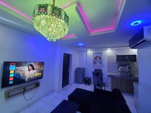 uma sala de estar com uma televisão e um lustre em Dinero Rose-2 Bedroom Apartment em Lagos