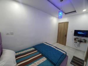 Cama pequeña en habitación con TV en Dinero Rose-2 Bedroom Apartment, en Lagos