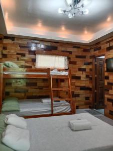 a bedroom with two bunk beds and a wall of wood at Woodland Inn in El Nido