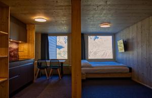 Zimmer mit einem Bett, 2 Stühlen und einem Fenster in der Unterkunft Frutt Living in Kerns