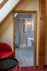 a bathroom with a shower and a red chair at Fichtelberghaus in Kurort Oberwiesenthal